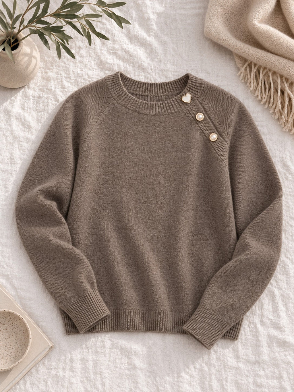 Knit sweater with pearl shoulder buttons laid flat